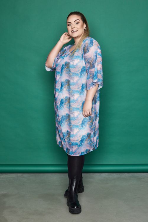 Plussize kjole med blåt og lyserødt skyprint, trekvartærmer og rund hals, stylet med sorte leggings og ankelstøvler.