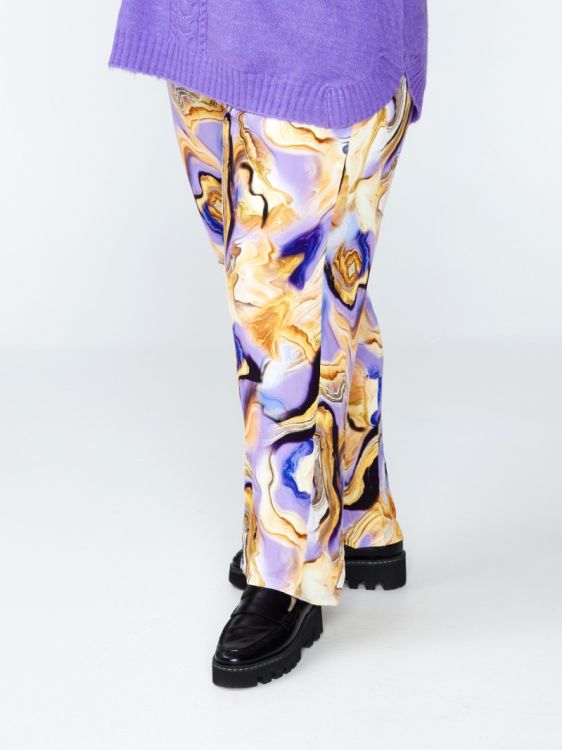 Plussize mønstrede bukser med abstrakt design i lilla og gyldne nuancer, vist med sort fodtøj og lilla striktrøje.