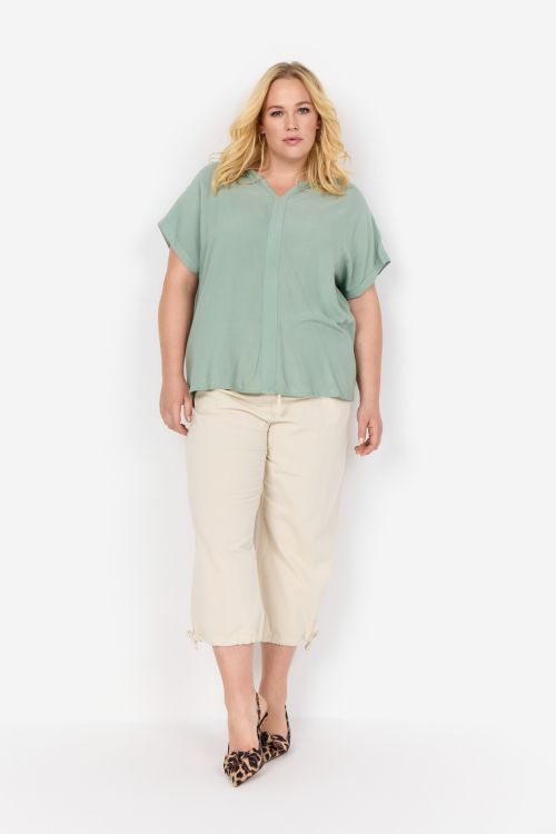 Casual plussize-udstyr med lysegrøn bluse og beige capri-bukser, komplet med dyreprint-fladsko.