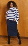 Stående model i stribet sweater og blå nederdel med slids, kompletteret med sorte støvler, viser eksempel på plus size mode.