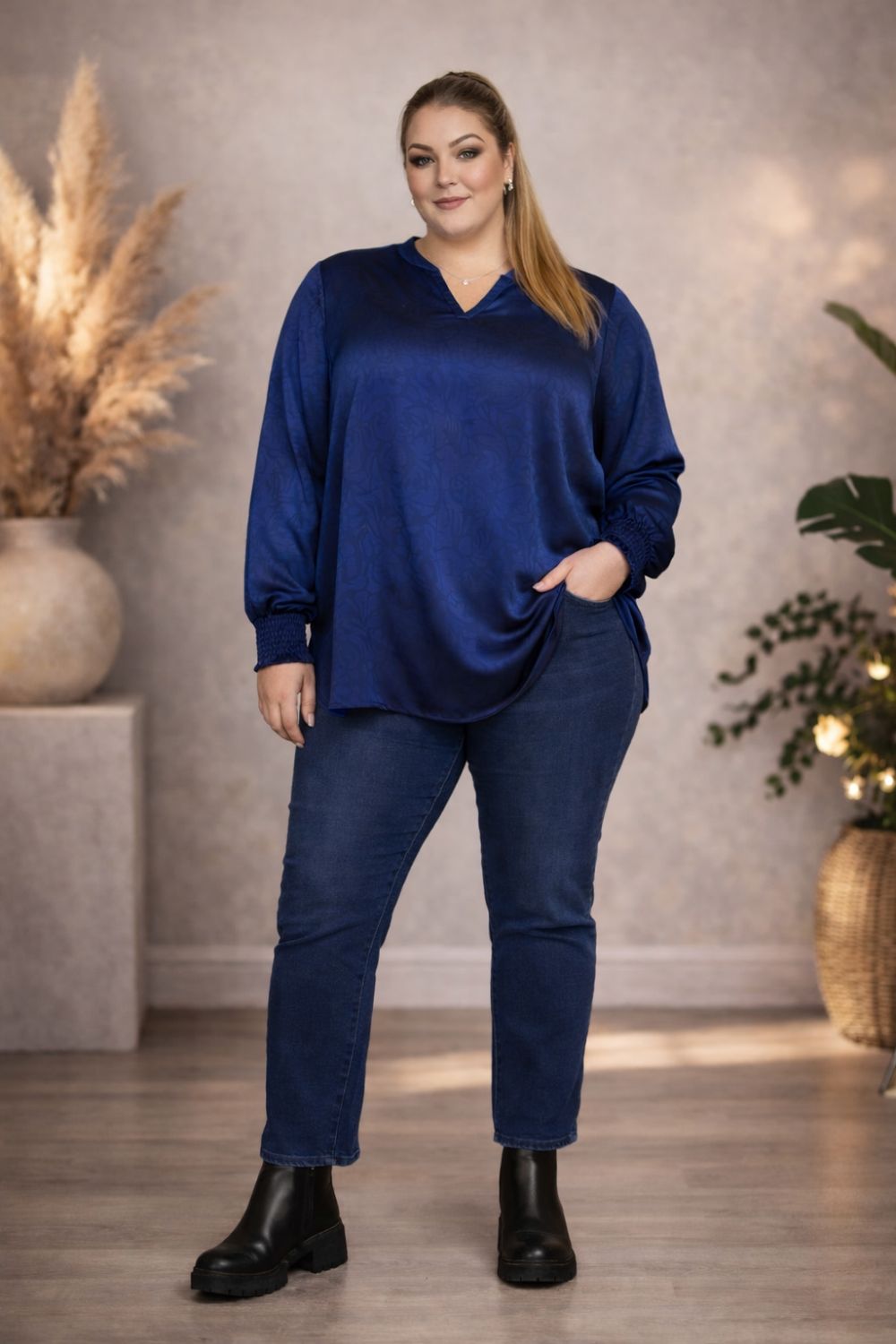 Elegant plussize blå mønstret bluse og bukser mod blødt baggrundslærred, ideel til hverdag eller kontor.